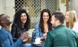 Friends together enjoying a coffee, as the topic of spending on experiences and affordability comes up