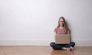 A renter sits on the floor of her new apartment, comparing insurance rates