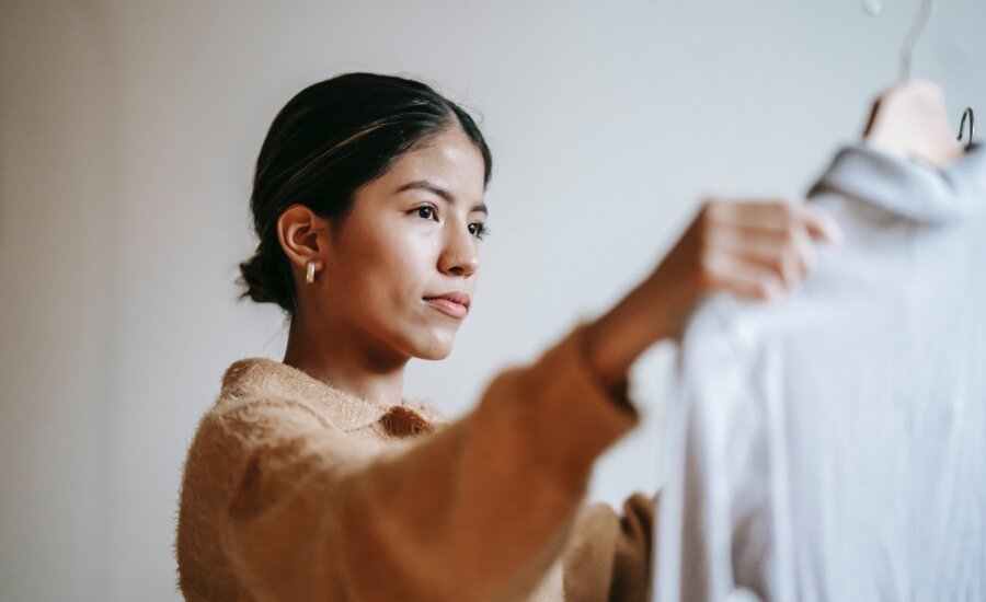 A woman considers whether or not to pack a shirt as she prepares to move