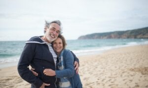 A couple nearing retirement embrace on the beach