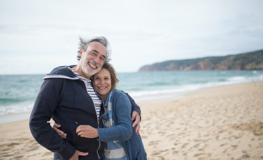 A couple nearing retirement embrace on the beach