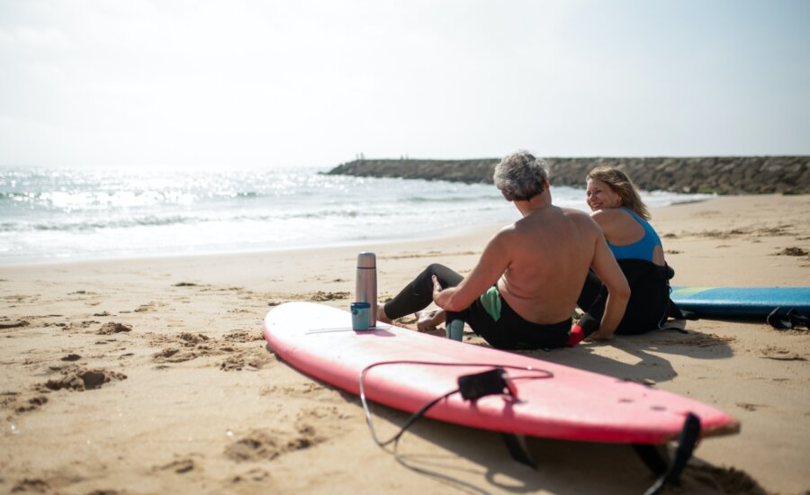 A retired couple sit on the beach after surfing