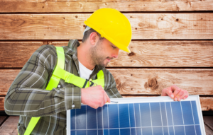 A man in a hard hat holds a solar panel