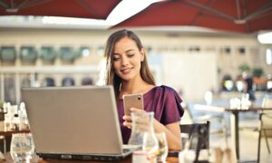 While dining on a patio, a woman reviews secured credit card options on her phone