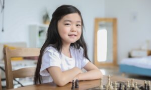 A young girl smiles as she plays chess