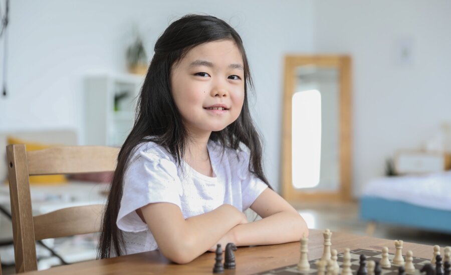 A young girl smiles as she plays chess