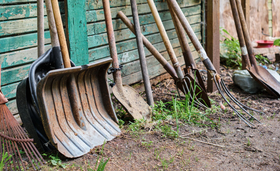 Several shovels and picks lean against a wall