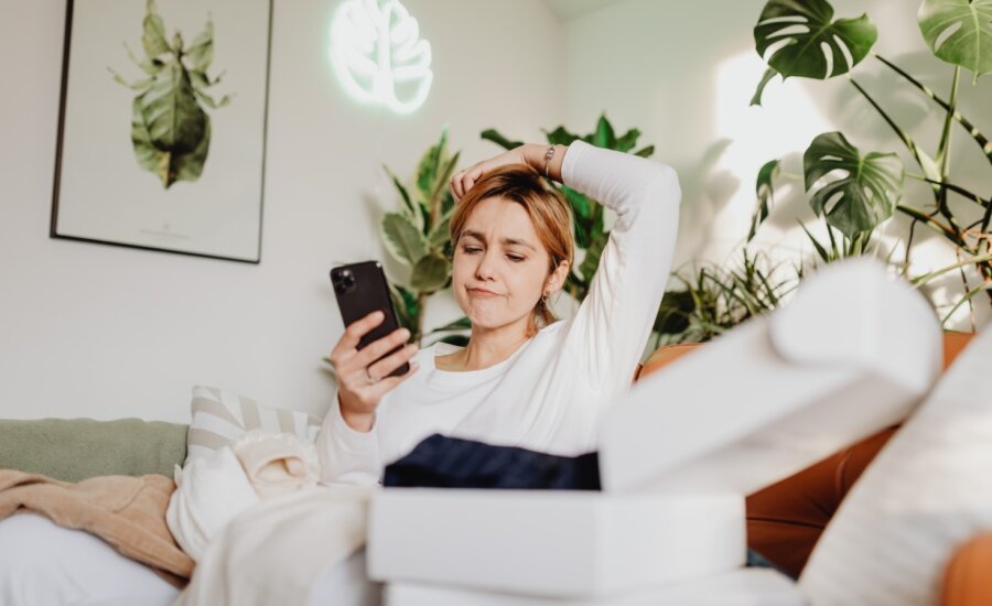 A woman sits on the couch looking at her phone