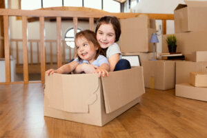 Two young sisters hugging in a cardboard box after moving into a new home