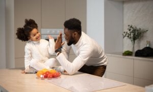 A father high-fives his daughter in the kitchen