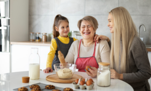 A grandmother, mother and young girl bake cookies together