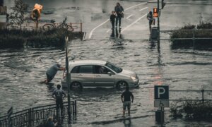 A man pushes his vehicle along a flooded road