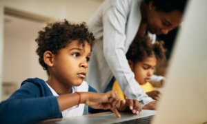 A young boy uses a laptop in class