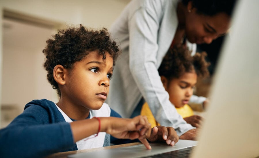 A young boy uses a laptop in class