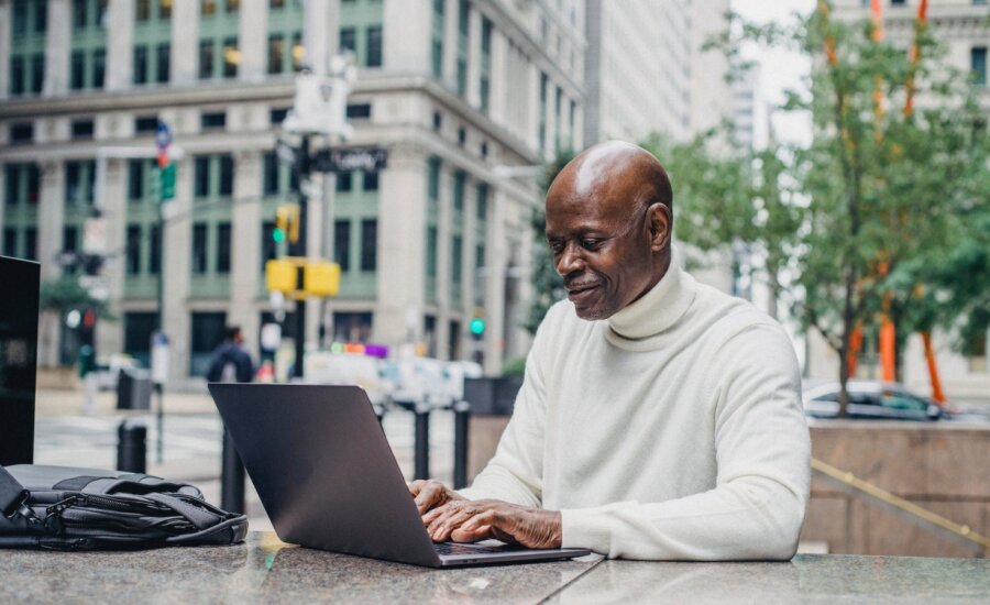 A man reviews OAS residency rules on his laptop near a busy intersection