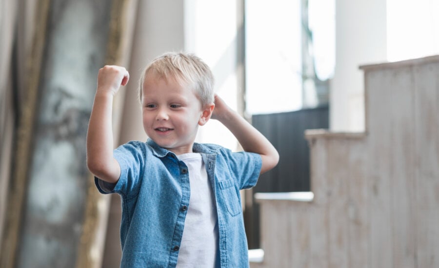 A toddler boy flexes his arm muscle