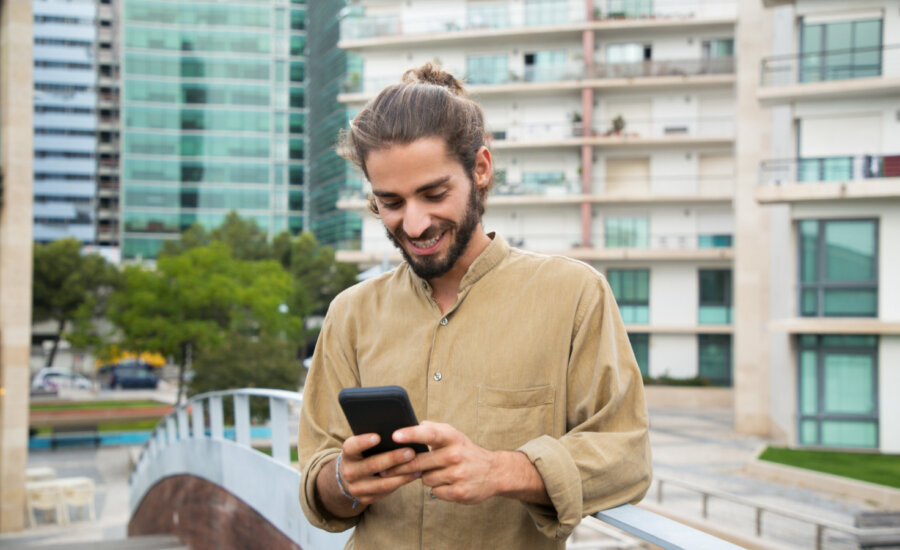 A young man smiles at his mobile phone.