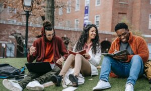 International students in Canada laugh and talk while sitting outsideon campus.