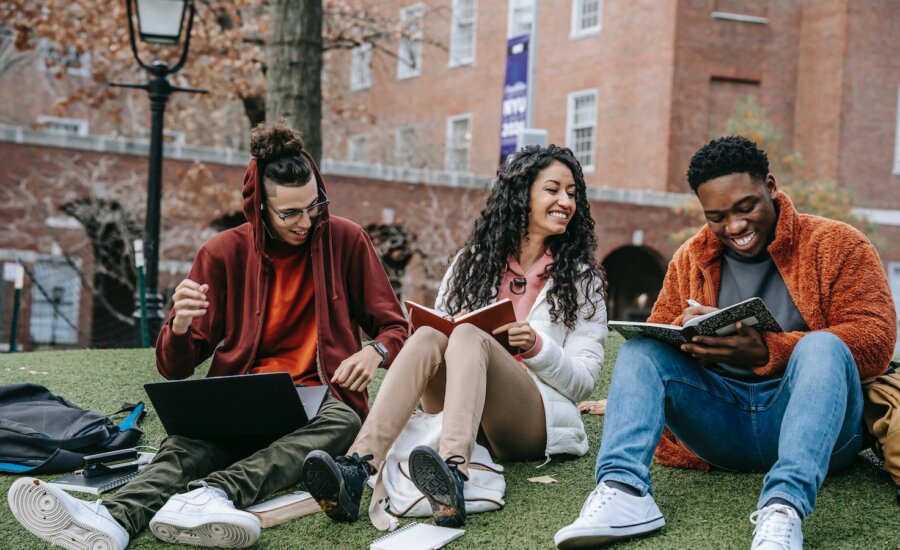 International students in Canada laugh and talk while sitting outsideon campus.