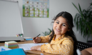 Smiling young girl sits at a desk