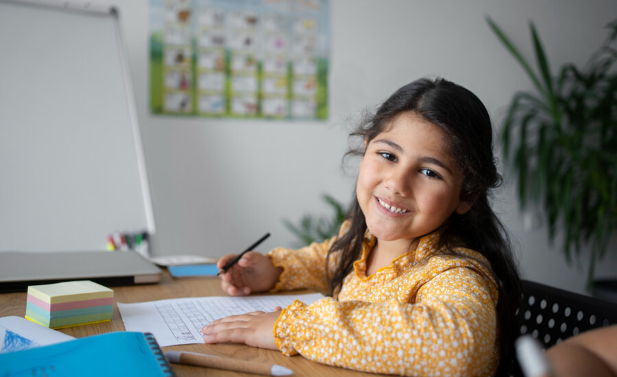 Smiling young girl sits at a desk