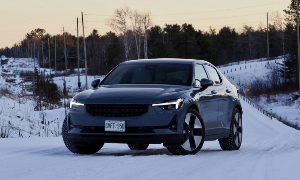 A dark-coloured Polestar 2 sedan on a snowy road