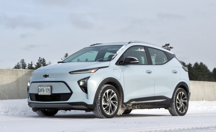 A Chevrolet bolt EV sits on a snowy road