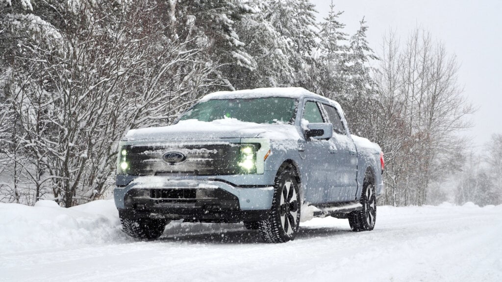 A blue Ford F-150 Lightning on a snowy road