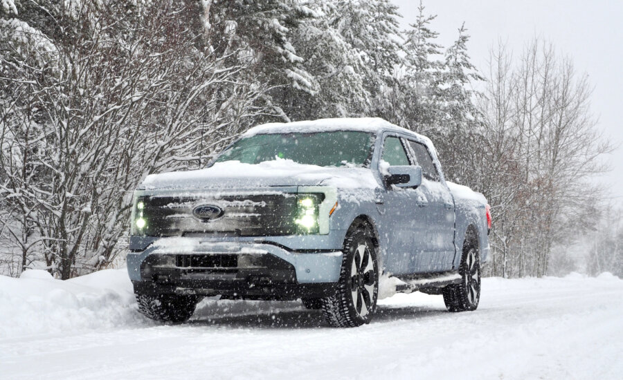 A blue Ford F-150 Lightning on a snowy road