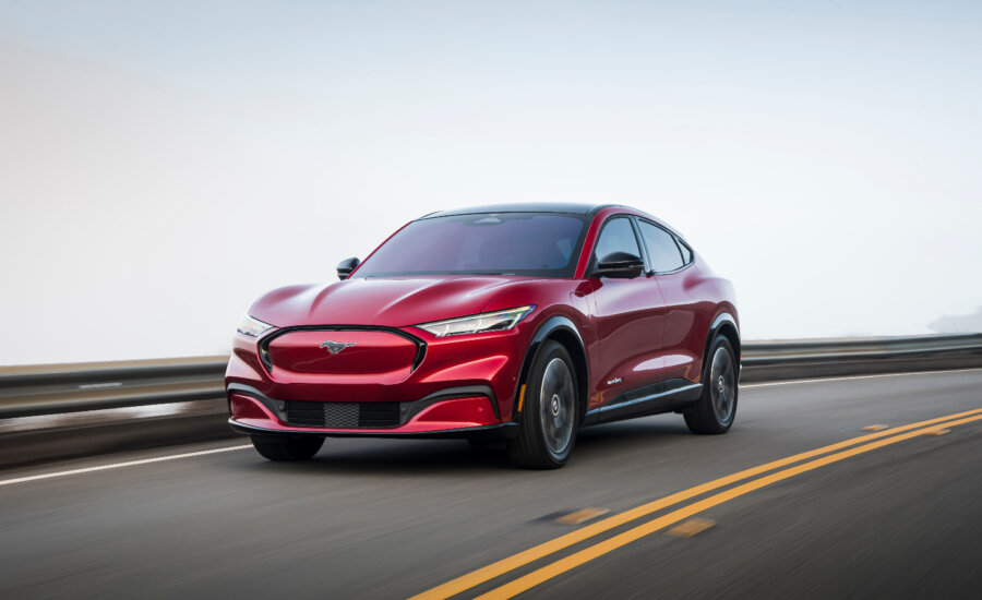 A red Mustang Mach-E drives on a highway