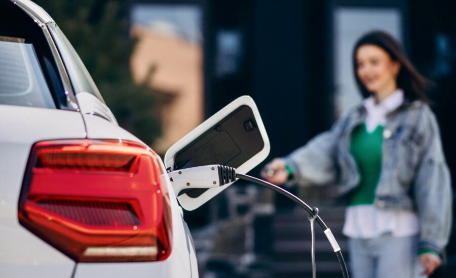 A woman charges her EV on her driveway