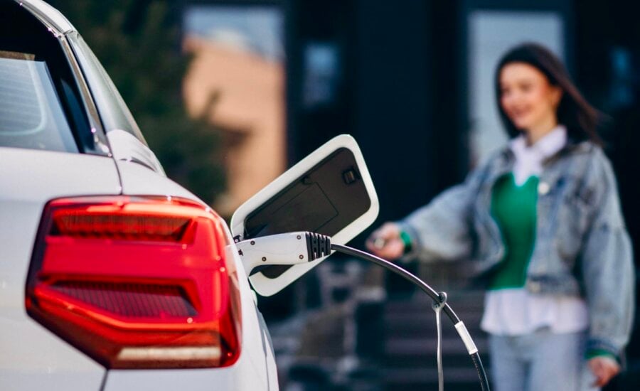 A woman charges her EV on her driveway