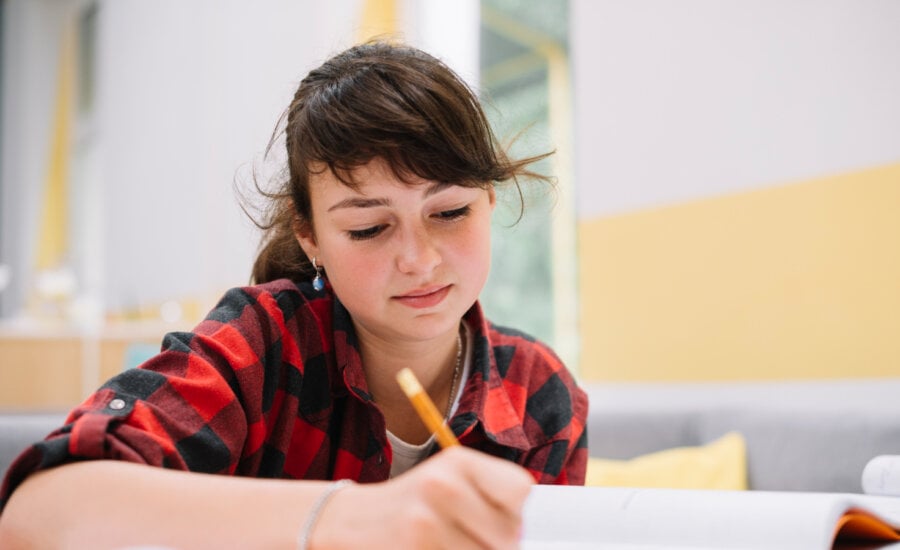 A teenage girl writes notes in class