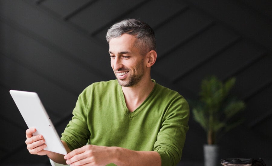 A smiling man in his forties looks at his financial info on a tablet