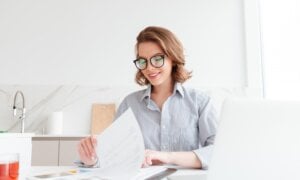 A woman reviews tax slips while completing her return online in the kitchen