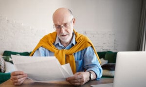 A wealthy older man reads his insurance policy