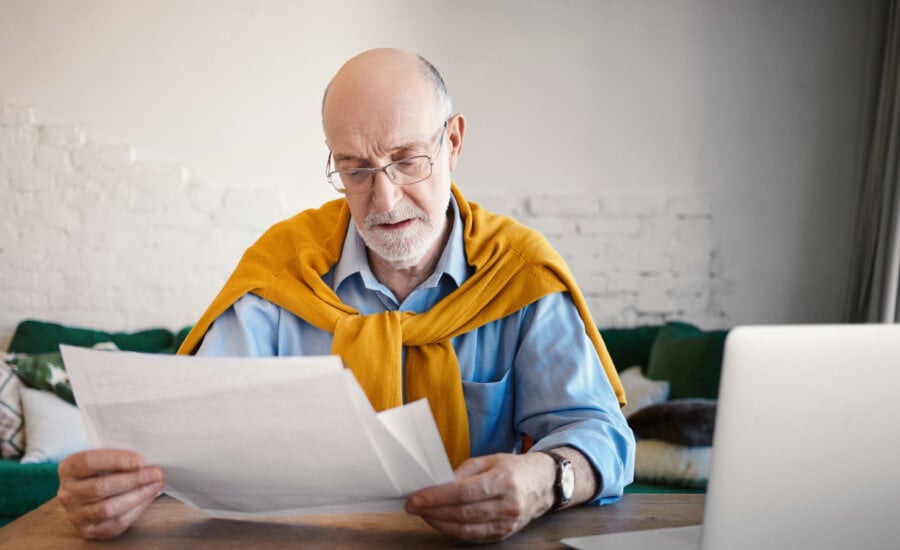 A wealthy older man reads his insurance policy