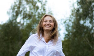 A woman smiling after learning what she should do with $100,000