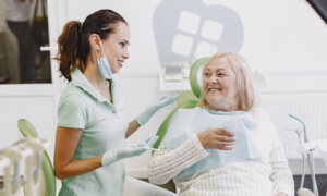 A hygienist talks to a senior-age woman in a dental clinic