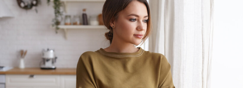 A worried young woman looks out her kitchen window