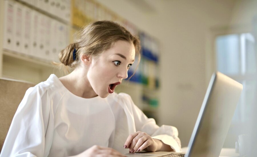 A young woman looks shocked by rising crypto prices on her computer