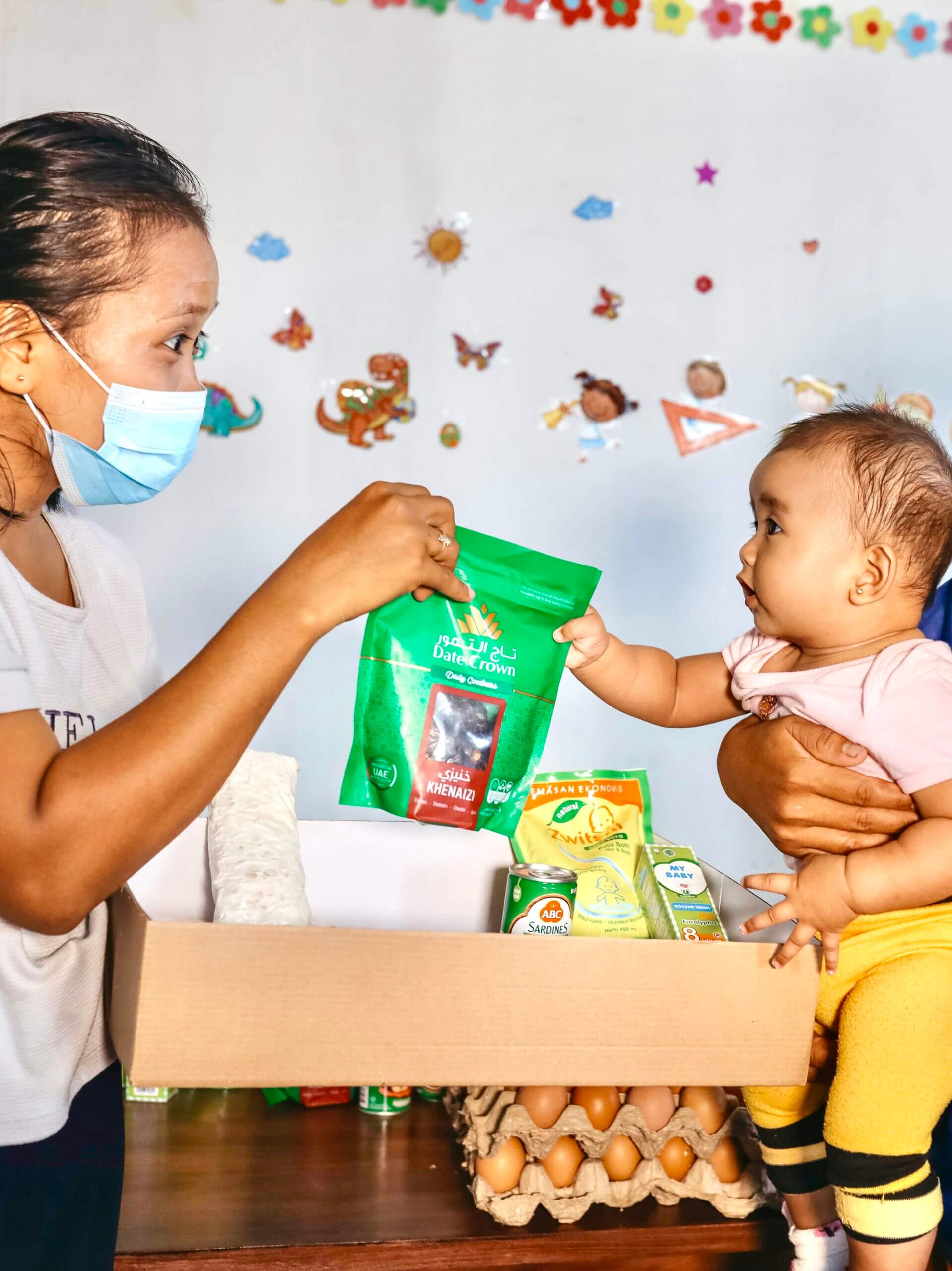 A charity worker gives a woman and her baby a package of food