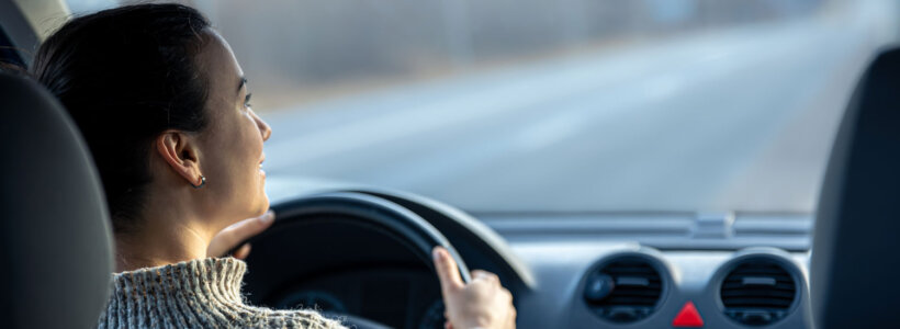 A woman driving on an Alberta highway, wondering why auto insurance is so expensive in the province.