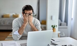 A man rubs his eyes in disbelief after discovering that he's a victim of fraud