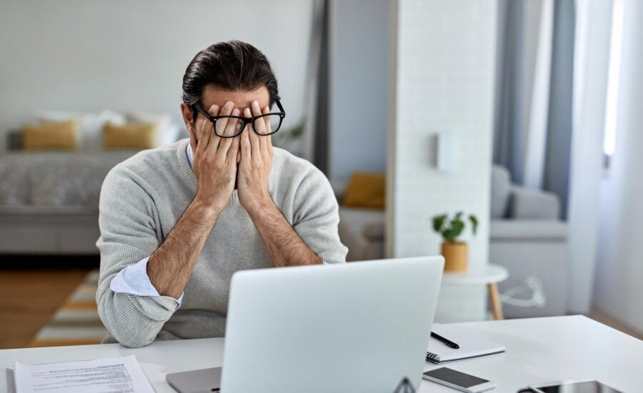 A man rubs his eyes in disbelief after discovering that he's a victim of fraud