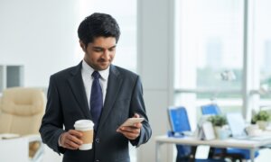 A man reviews his capital losses on his cellphone at the office