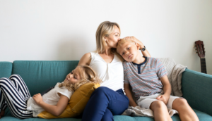 A mom holds her two young kids on a sofa