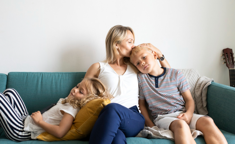 A mom holds her two young kids on a sofa