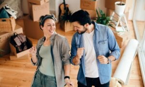 A man and woman celebrate the purchase of their second home by dancing in the living room