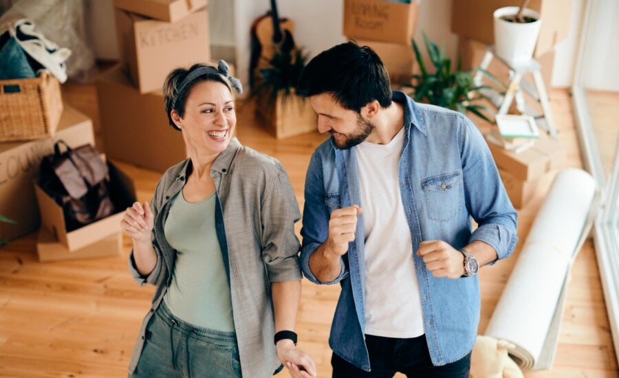 A man and woman celebrate the purchase of their second home by dancing in the living room